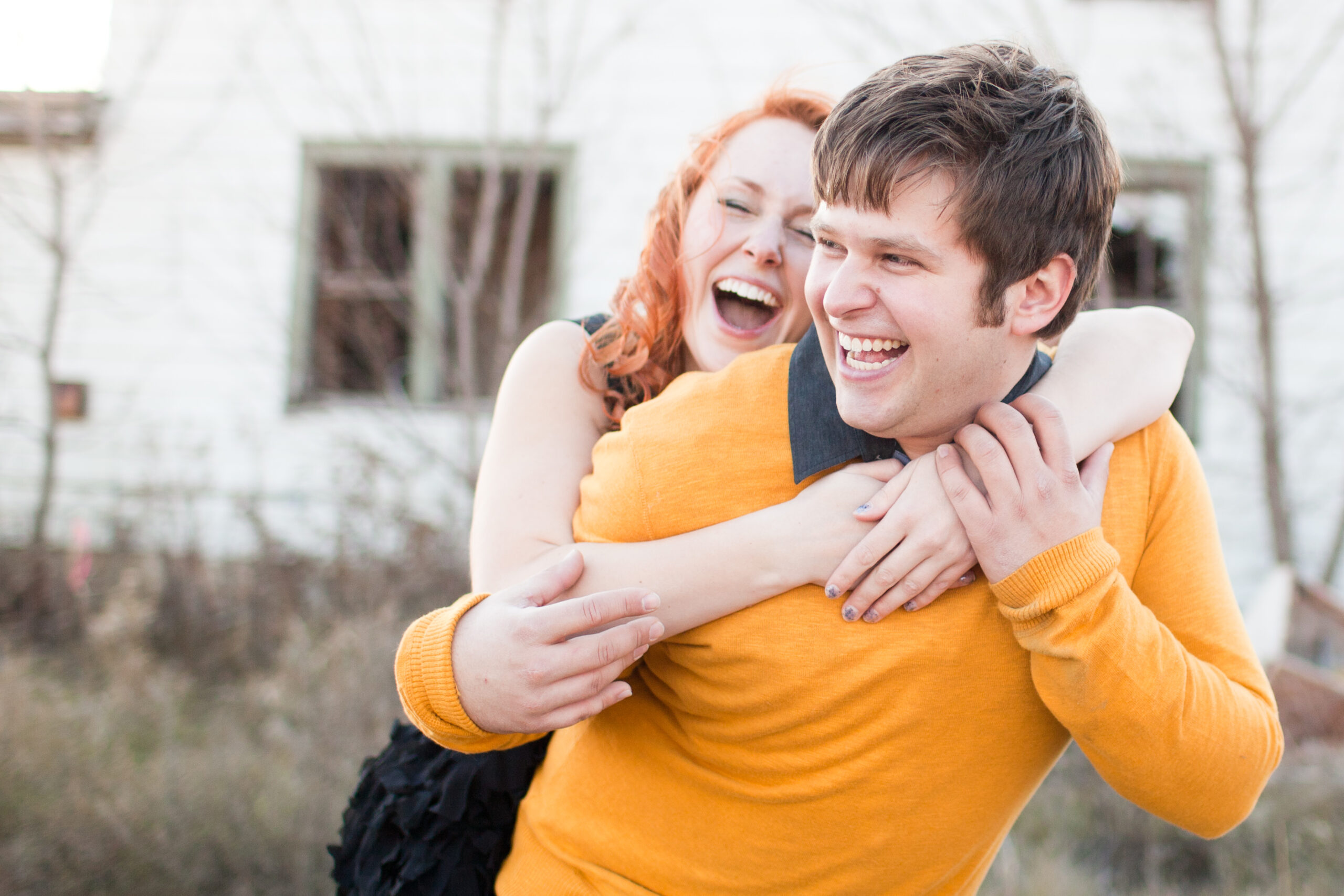 A couple embraces in a happy, excited manor in front of a house.