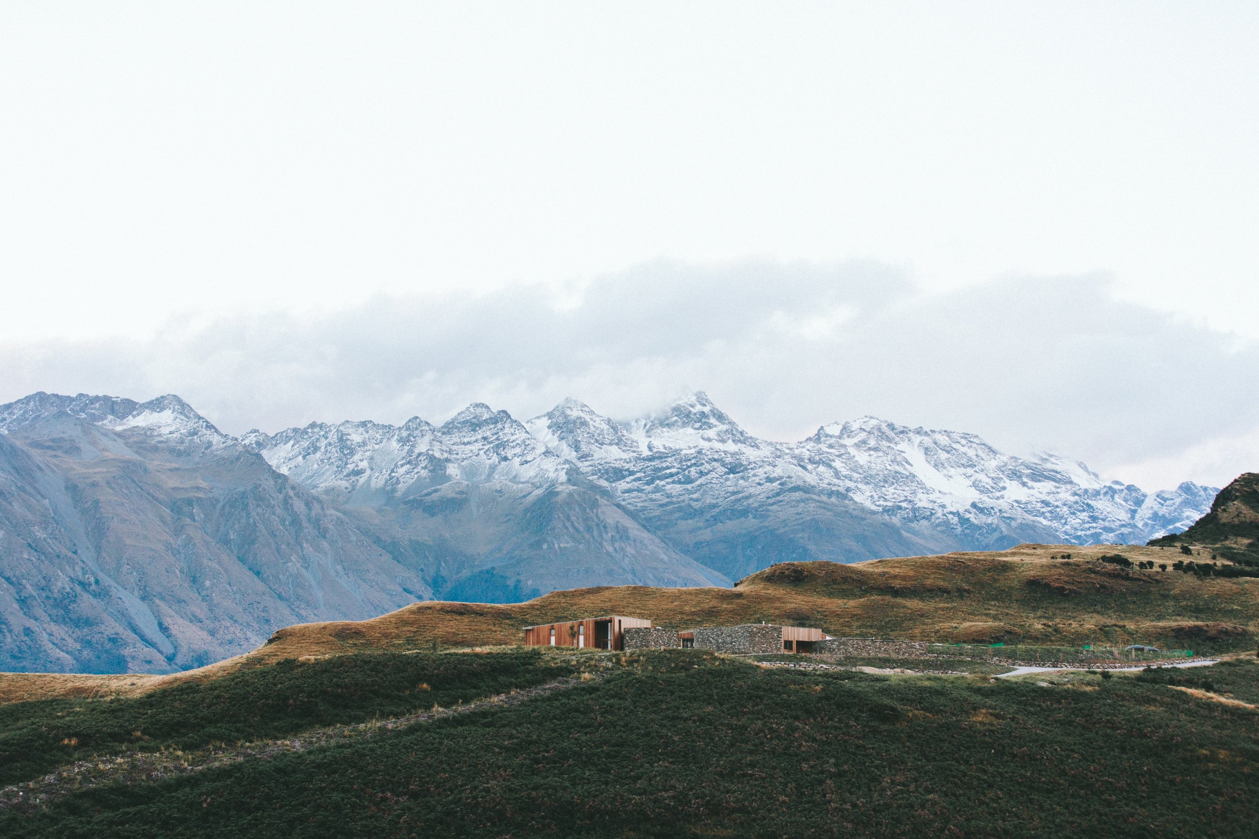 House on a hillside with snow-capped mountains in the background