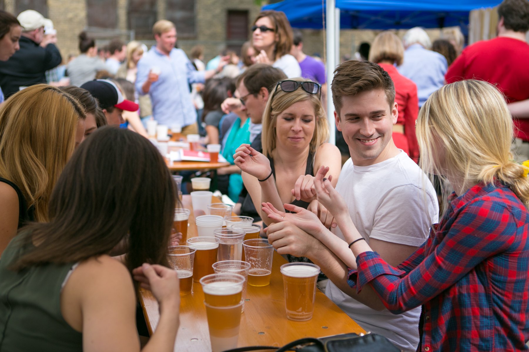 People socializing at an outdoor event with drinks on a table.