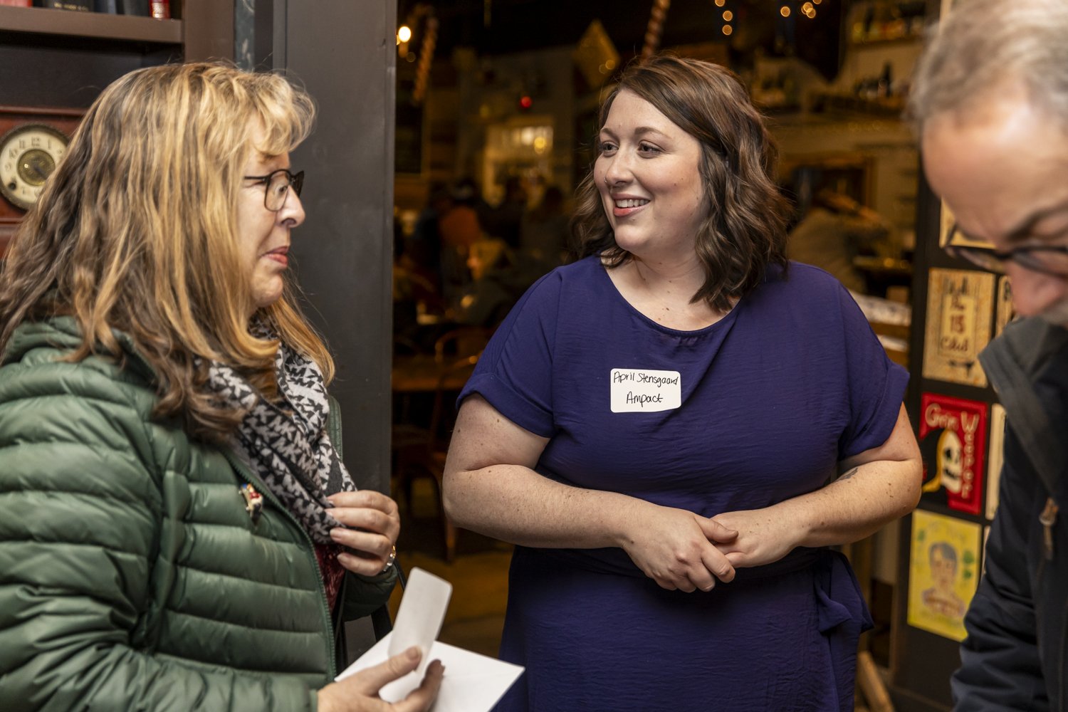 Three people engaged in conversation at an indoor gathering.