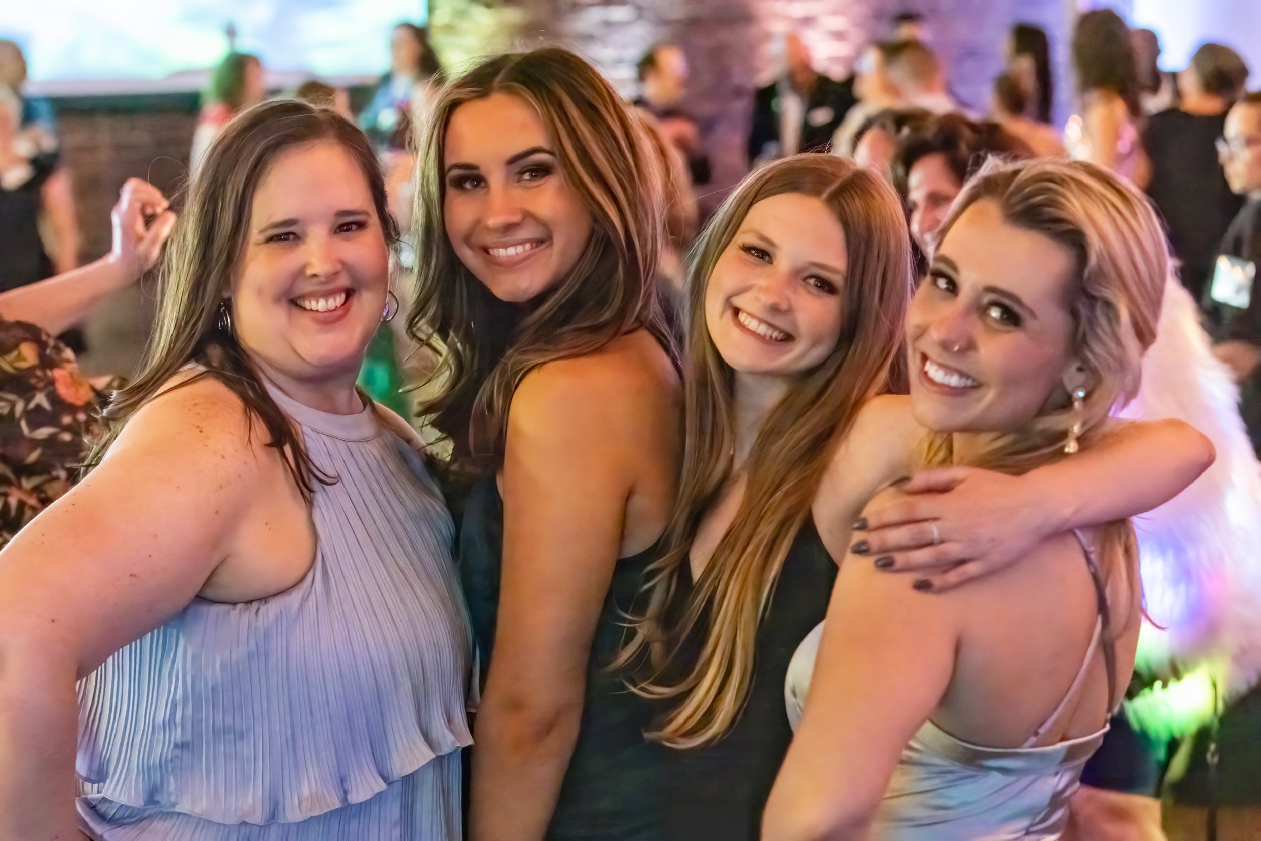 Four women smiling and posing at a party.