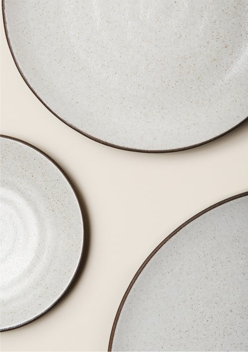 Set of three speckled ceramic plates with dark rims on a light background.