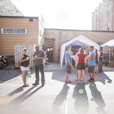 Group of people socializing outside Boom Island Brewing Company during daytime.