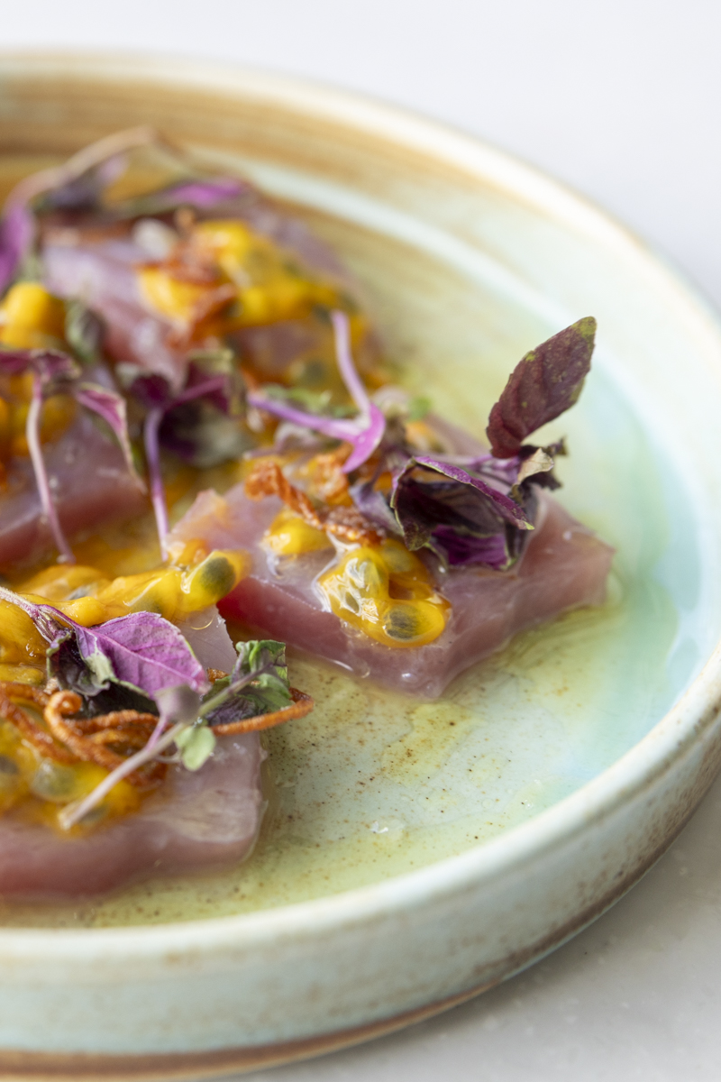 Close-up of ahi sashimi with lilikoi passion fruit sauce and purple micro greens at KOAST restaurant Wailea
