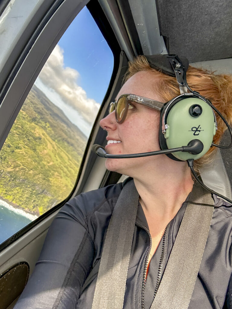 Photographer smiling aboard Maverick Helicopters tour over Maui coastline