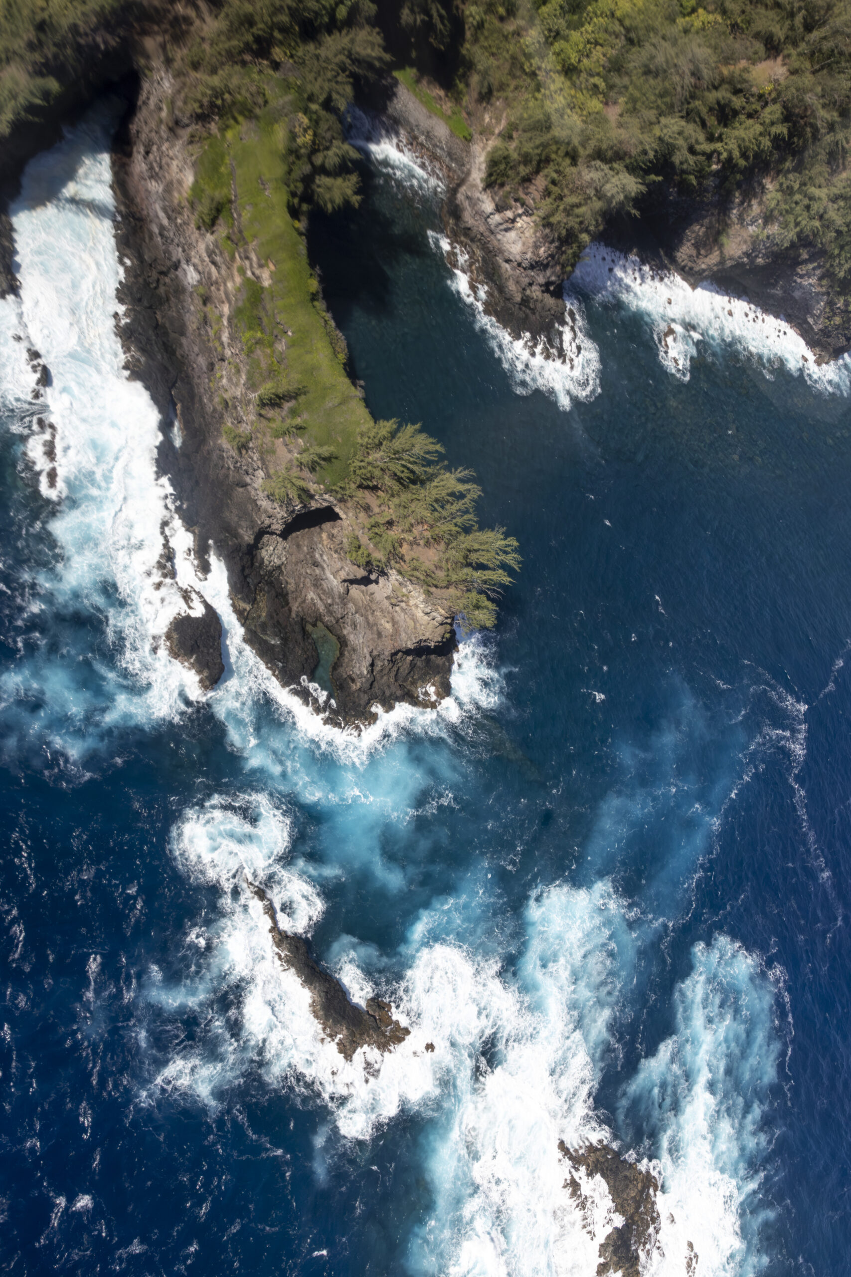 Aerial view of dramatic sea stack and waterfall along Maui north shore cliffs from helicopter
